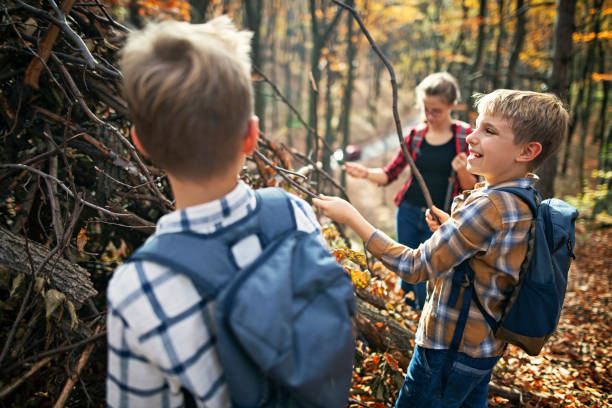 bambini che costruiranno un rifugio antiaderente nella foresta autunnale - hut foto e immagini stock