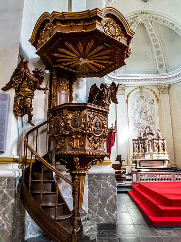 Malmedy, Belgium - April 08, 2015: Interior view of the Cathedral of Malmedy, the beautiful wooden pulpit from 1770 in the foreground, the choir in the background