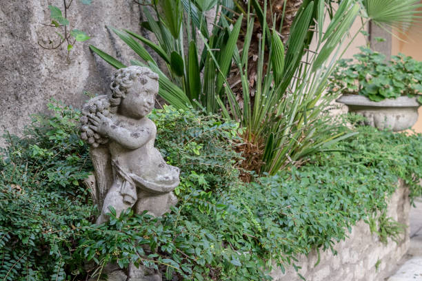 Wall in the garden with green plants and a small sculpture