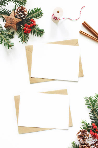 istock Christmas composition. Blank greeting card, envelope mock-up scene. Pine cones, fir tree branches, red rowan berries and wooden stars on white table background. Flat lay, top view, vertical. 1063391240