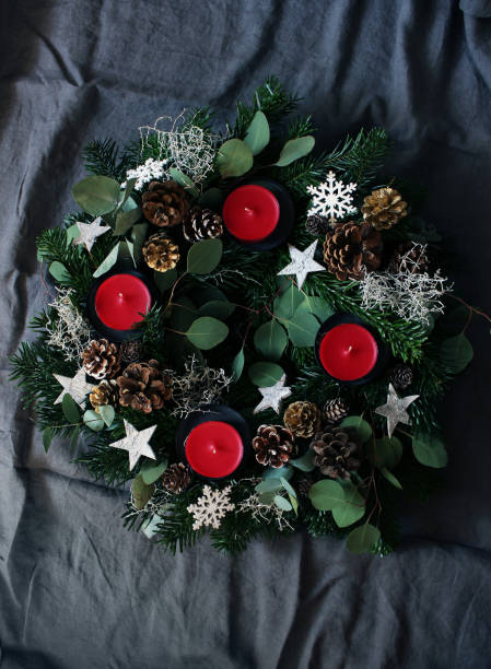 composizione natalizia della corona dell'avvento su sfondo di lino da tavola grigio scuro. realizzato con rami di abeti sempreverdi, foglie di eucalipto, fiocchi di neve, pigne dorate e naturali. lay piatto, vista dall'alto. - christmas branch pine tree evergreen tree foto e immagini stock