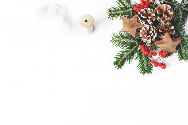 istock Christmas festive styled composition. Decorative banner. Pine cones, fir tree branches, red rowan berries, wooden stars and silk ribbon on white table background. Negative space. Flat lay, top view. 1063391312