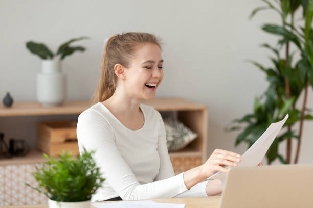 istock Happy laughing woman sitting at the desk reading documents 1063392596