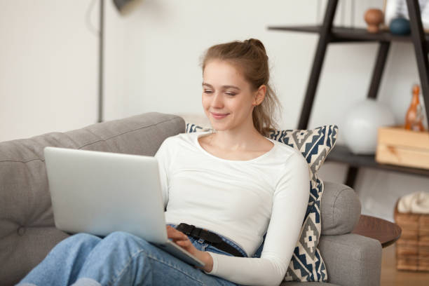 istock Attractive girl sitting on couch using laptop 1063392676