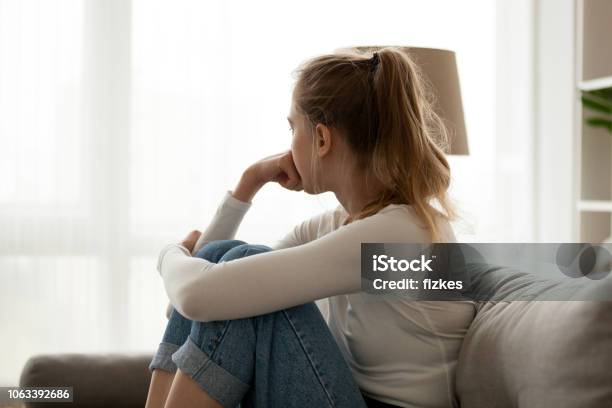 Upset Woman Sitting On Couch Alone At Home Stock Photo - Download Image Now - Women, Teenager, Sadness