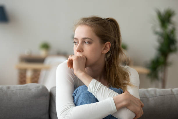 Sad woman sitting on couch alone at home Head shot woman anxious worried woman sitting on couch at home. Frustrated confused female feels unhappy, problems in personal life, quarrel break up with boyfriend and unexpected pregnancy concept worried stock pictures, royalty-free photos & images