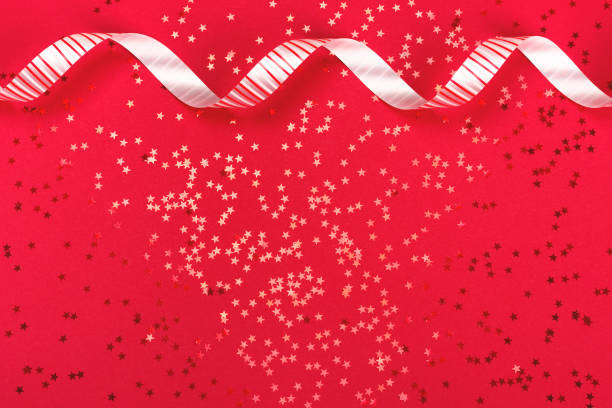 istock Metallic star shaped confetti on festive red background. 1063393876