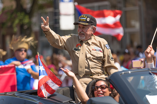 Chicago, Illinois, USA - June 16, 2018: The Puerto Rican People's Parade, Puerto Rican Korea war veteran carrying the puerto rican flags, waving at spectators