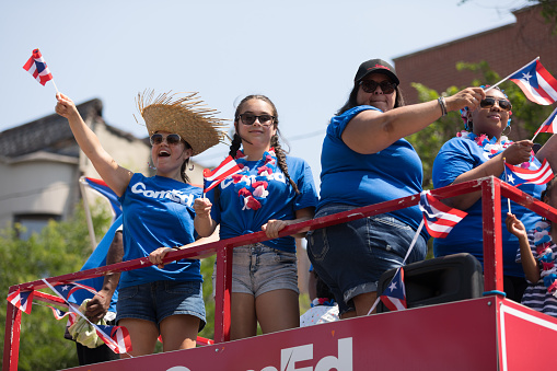 Chicago, Illinois, USA - June 16, 2018: The Puerto Rican People's Parade, Puerto Rican people on top of a float celebrating waving puerto rican flags during the parade