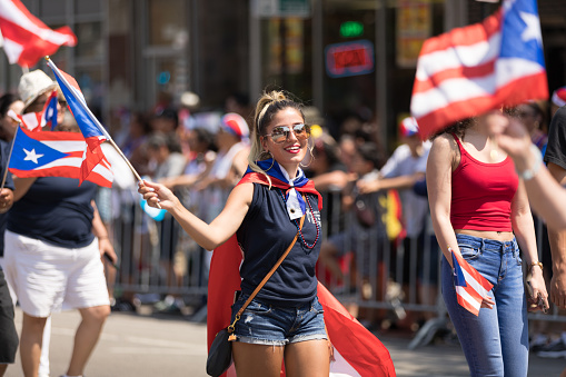 Chicago, Illinois, USA - June 16, 2018: The Puerto Rican People's Parade, Puerto rican woman waving the puerto rican flag going down the road during the parade