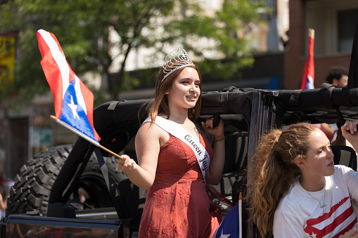 Chicago, Illinois, USA - June 16, 2018: The Puerto Rican People's Parade, Puerto rican woman waving the puerto rican flag going down the road during the parade