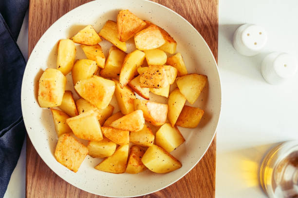 istock Top view on roasted potato in a white pan on a kitchen table. Modern style, vegetarian food. 1063400348