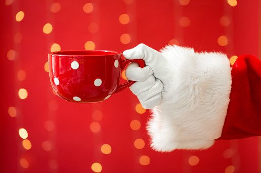 Santa holding a coffee cup on a shiny light red background