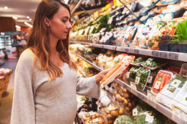 pregnant woman shopping for healthy food in supermarket - woman reaching into handbag imagens e fotografias de stock