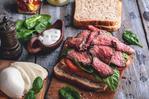 istock Steak sandwich, sliced roast beef, cheese,spinach leaves,tomato,white sauce 1063419514