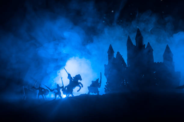 istock Medieval battle scene with cavalry and infantry. Silhouettes of figures as separate objects, fight between warriors on dark toned foggy background with medieval castle. Night scene. Selective focus 1063424518