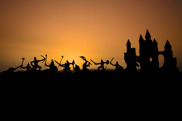 istock Medieval battle scene with cavalry and infantry. Silhouettes of figures as separate objects, fight between warriors on sunset foggy background. 1063424552