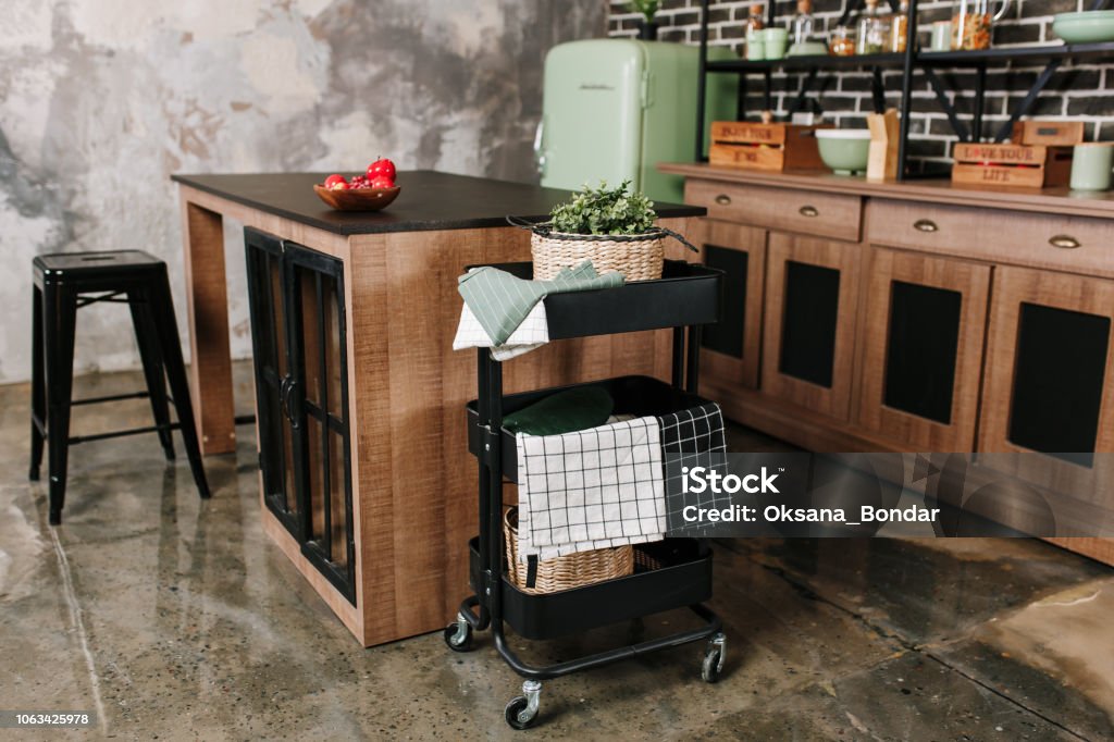 Cozy loft kitchen with dinning table, chairs and metal storage racks on wheels - trolley Cozy loft kitchen with dinning table, chairs and metal storage racks on wheels - trolley. Shopping Cart Stock Photo
