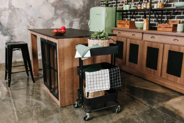 Cozy loft kitchen with dinning table, chairs and metal storage racks on wheels - trolley.