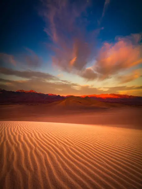 This is a photograph of Death Valley sand dune with colorful clouds in California, USA