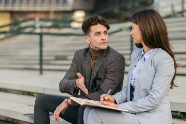 istock Two young business colleagues sitting on staircase and discussing. 1063453110