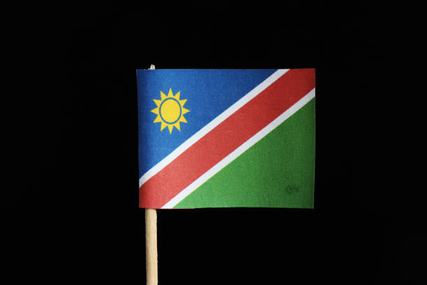 A national flag of Namibia on toothpick on black background. A consists of a white-edged red diagonal band radiating from the lower hoist side corner. The upper is blue with yellow sun and lower green A national flag of Namibia on toothpick on black background. A consists of a white-edged red diagonal band radiating from the lower hoist side corner. The upper is blue with yellow sun and lower green. bushveld photos stock pictures, royalty-free photos & images