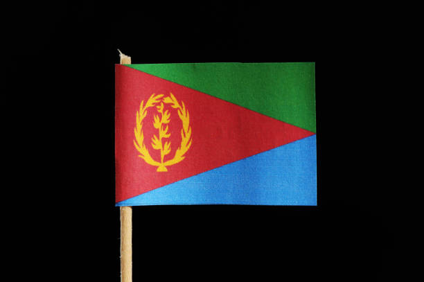 A national and official flag of Eritrea on toothpick on black background. A three triangles which one is red with coat of arms and second is the upper is green and lower is blue.