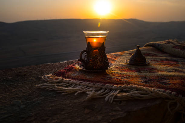 istock Arabian tea in glass on a eastern carpet. Eastern tea concept. Armudu traditional cup. Sunset background. Selective focus 1063466162