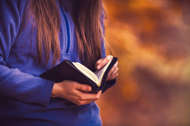 istock Autumn setting, warm colours, girl reading the bible 1063469718