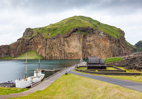 Looking at the peak of Heimaklettur in Vestmannaeyjar (Westman Islands) in Iceland. Heimaklettur is a towering peak that looks over the main village on Heimaey, climbing it is a rite of passes for local children on the island.