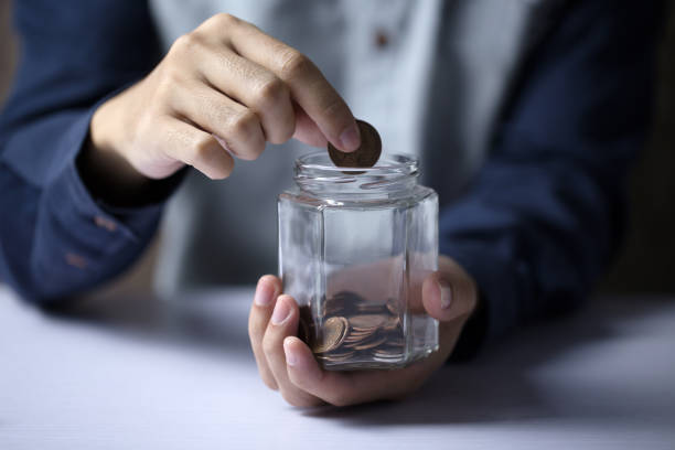 istock Hand Putting Money To Glass Bottle 1063484616