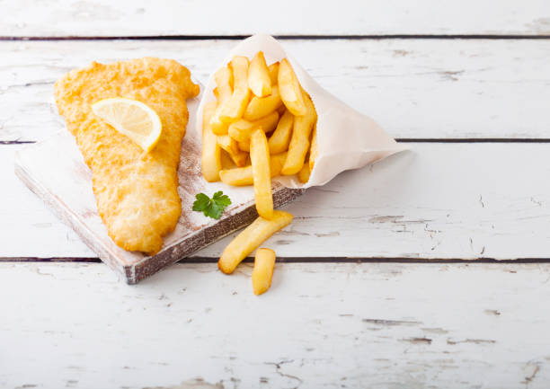 istock Traditional British Fish and Chips with tartar sauce on chopping board on white woode background. Space for text 1063484670