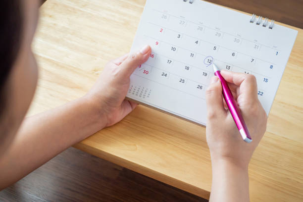 istock calendar page with female hand holding pen on desk table 1063498218
