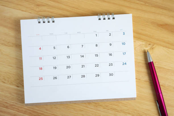 istock Calendar page with pen on wooden desk table 1063498240