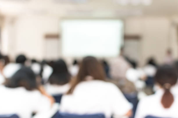 istock School classroom blurred background of college or university students back view sitting in class in seating rows studying learning course in lecture room with white projector screen in front 1063499146
