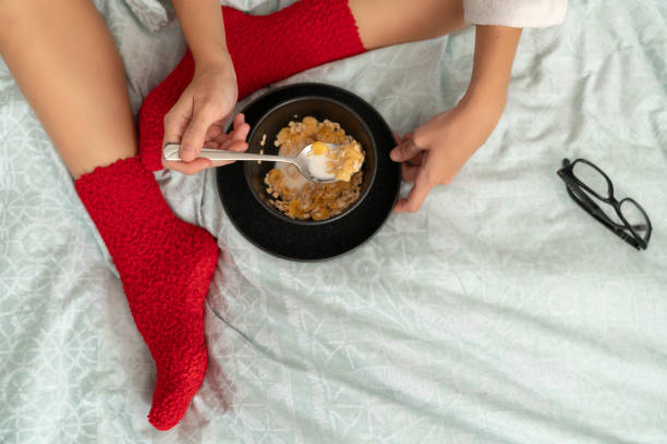 istock Woman in red socks sitting on bed and eating cornflakes 1063500918
