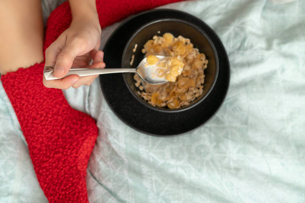 istock Woman in red socks sitting on bed and eating cornflakes 1063500922