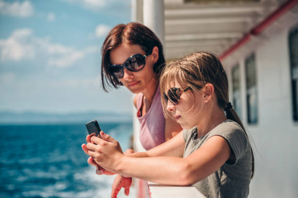 Mother and daughter traveling on ferry and taking pictures Mother and daughter traveling on ferry and taking pictures with smart phone at ship deck ferry deck girls stock pictures, royalty-free photos & images