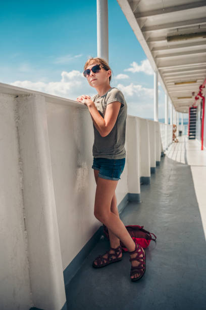 Girl standing on a ship deck at ferry Girl wearing sunglasses standing at ship deck on a ferryboat and looking at the sea ferry deck girls stock pictures, royalty-free photos & images