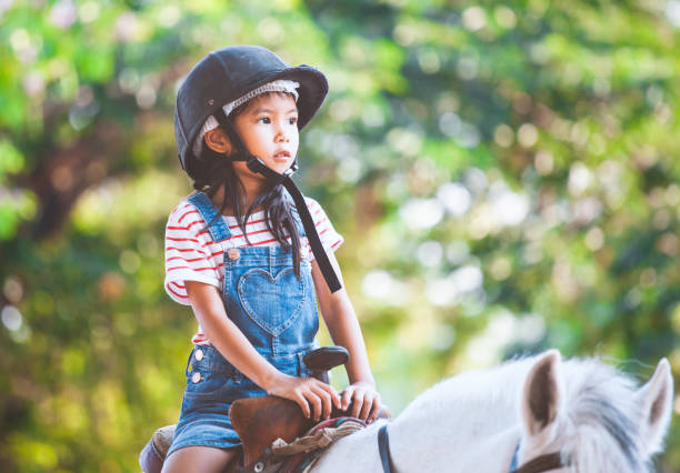 süße asiatische kind mädchen auf einem pferd in der farm mit spaß - pony fotos stock-fotos und bilder