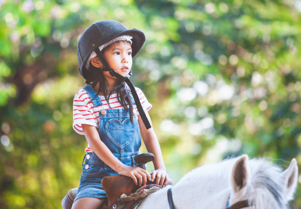 ragazza asiatica carina a cavallo nella fattoria con divertimento - horse child pony little girls foto e immagini stock