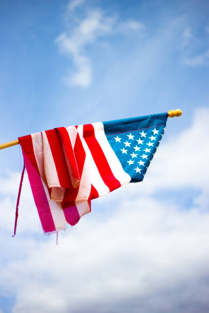 istock Tattered Old US Flag Hanging; Sky Background 1063553690