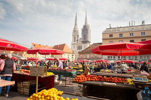 Zagreb, Croatia - October 2018: Zagreb Farmers Market with people shopping and the famous Zagreb Cathedral in the background.