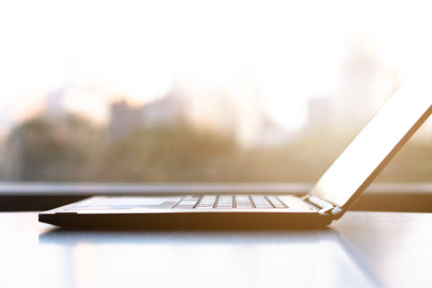 istock Side View of office laptop computer on desk table on with city background 1063559662