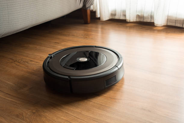 robot vacuum cleaner on wood,laminate floor.smart life concepts - vacuum cleaner imagens e fotografias de stock