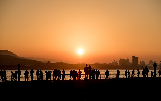 TAIWAN, TAIPEI, TAMSUI - JANUARY 2015: People hang out along the riverside of TAMSUI, TAIWAN. They enjoy the sunset and chill out. This is a perfect place for family, locals and friends. Relaxing day.