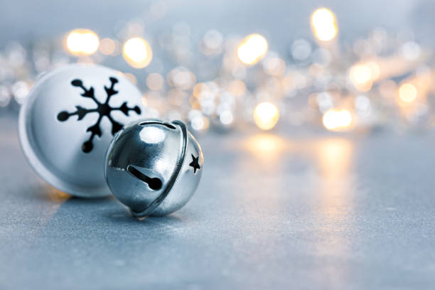 festive christmas jingle bells on grey background with blurred garland lights