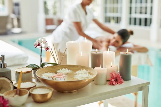 Relaxation starts now Cropped shot of various pampering essentials in a spa with a woman getting a beauty treatment in the background beauty treatment relaxation women carefree stock pictures, royalty-free photos & images