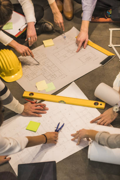 istock Team of unrecognizable architects analyzing blueprints on the floor. 1063601736