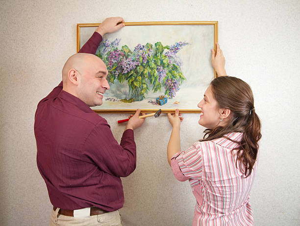 istock couple hanging up an art picture on their wall 106360461